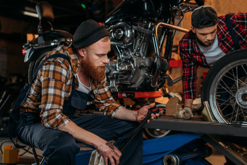 Fototapeta na wymiar handsome mechanics working together at custom garage