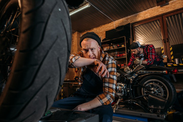 Plakat exhausted mechanic wiping sweat after work at garage