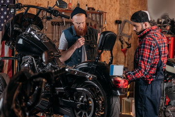 Fototapeta na wymiar repair worker talking to serious customer near motorcycle at garage