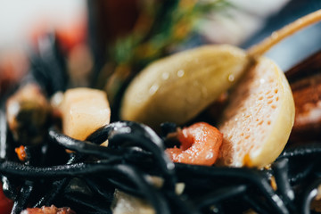 close-up view of gourmet spaghetti with cuttlefish ink, squid and mussels with octopus
