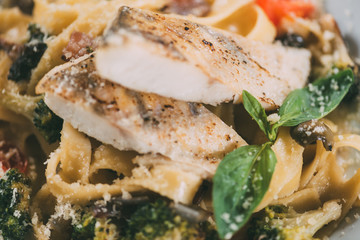 close-up view of delicious pasta with pike perch fillet, vegetables and parmesan cheese