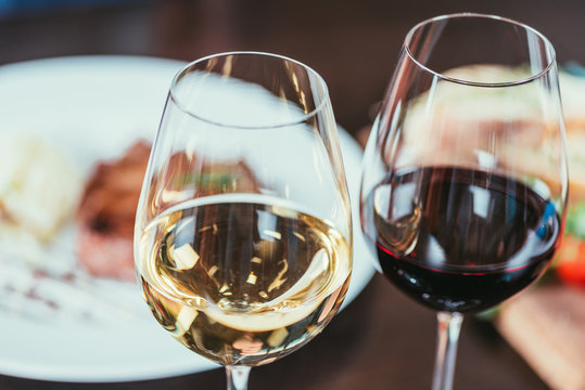 close-up view of two glasses with red and white wine on table in restaurant