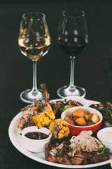 glasses of wine and plate with gourmet grilled vegetables and meat on table in restaurant