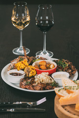 glasses of wine and plate with grilled vegetables and meat on table in restaurant