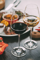 close-up view of glasses of wine and plate with grilled vegetables and meat on table
