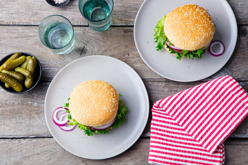 Burger on a plate with pickles. Wooden background. Top view.
