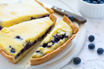 Tea time. Homemade blueberryy cheesecake, cups of tea, nuts and berry on white table cloth