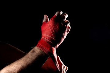 A boxer's red bandage on his hand isolated on dark blurred background, close-up.