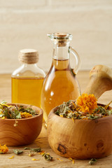 Picturesque composition of oil jars, pestle and mortar with motley grass over wooden background, selective focus.