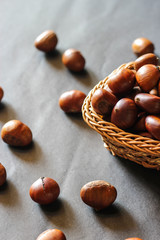 Fresh chestnuts on dark black rustic background. Pile of fresh chestnuts ready to roast shot over black antique background. Top view.
