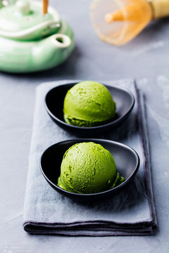 Matcha ice cream scoop in bowl on a grey stone background.