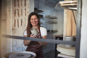 Smiling artisan examining a vase in her creative workshop