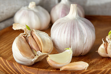 Garlic close up on wooden plate on rustic background, shallow depth of field, selective focus, macro.