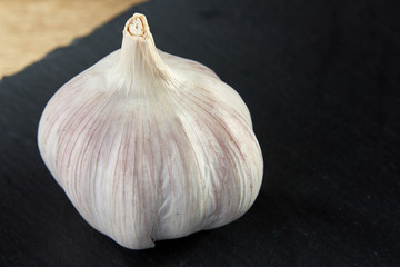 Garlic composition close up on black flat piece of board, macro, shallow depth of field, selective focus.