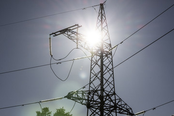 High voltage power line tower in the background of a bright sun