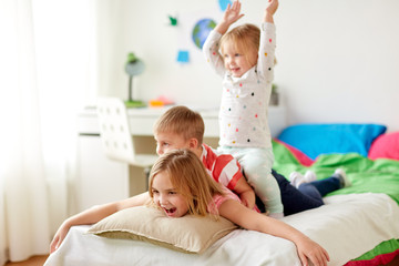 happy little kids having fun in bed at home