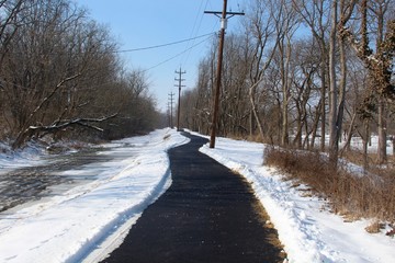 The long blacktop path in the snowy landscape.