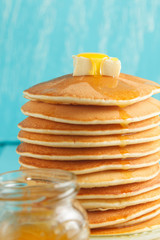 Close up of stack of pancake with honey, butter and jar of honey