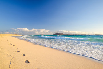 Stunning morning view of the islands of Lobos and Lanzarote seen from Corralejo Beach (Grandes Playas de Corralejo) on Fuerteventura, Canary Islands, Spain, Europe. Beautiful footprints in the sand. - obrazy, fototapety, plakaty