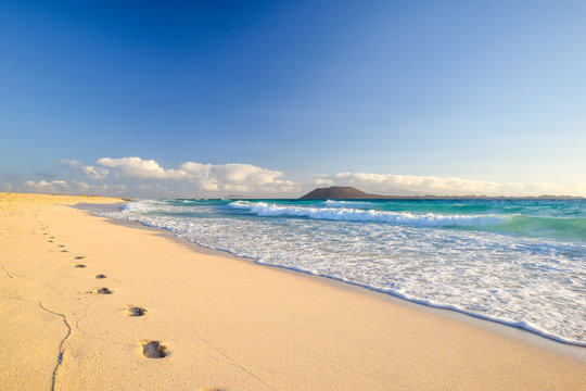 Stunning morning view of the islands of Lobos and Lanzarote seen from Corralejo Beach (Grandes Playas de Corralejo) on Fuerteventura, Canary Islands, Spain, Europe. Beautiful footprints in the sand.