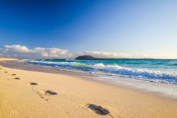 Stunning morning view of the islands of Lobos and Lanzarote seen from Corralejo Beach (Grandes Playas de Corralejo) on Fuerteventura, Canary Islands, Spain, Europe. Beautiful footprints in the sand.
