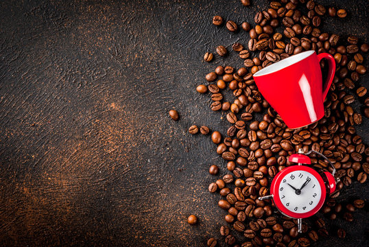 Concept of a cheerful, good start to the day, morning coffee. Dark rusty background with coffee beans, an alarm clock and a cup of coffee. Top view copy space