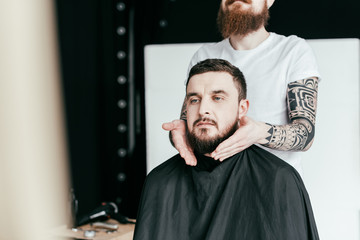 cropped image of barber styling customer beard at barbershop