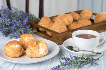 Many tasty cakes of Shue from custard paste with cream stuffing lie on a round plate on a  white...