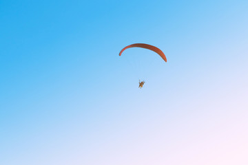 paramotor flying on blue sky and light of the sun.