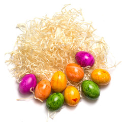 Colored eggs on the side of packing straw. Isolated. Easter 2018. top view