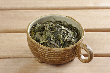 Ceramic cup with leaves of green, wooden desk