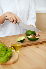 Diet. Female Hands Cutting Avocado In Kitchen.