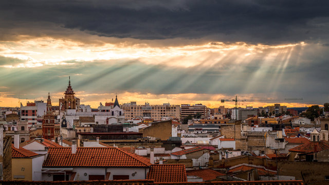 badajoz skyline with sun lights colandose among black clouds