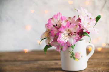A bouquet of flowers stands in a white mug