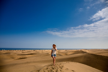 Fototapeta na wymiar Glückliche Frau sitz auf dem Sand in Maspalomas
