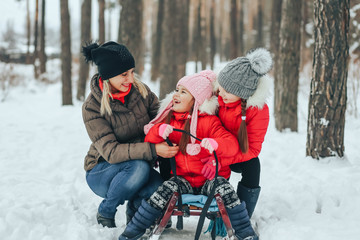 mother with her children playing in the winter forest