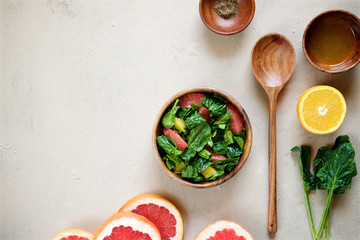 Fresh spinach salad with citrus. Light background, top view
