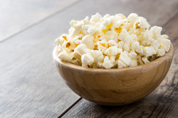 Popcorn in bowl on wooden table.