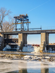 Fototapeta premium The dam on the river in the city in the winter. Icing of dam structures during the descent of water in winter