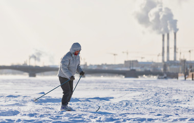 Woman skier riding on ice of the frozen Neva River at sunny day, winter in St.Petersburg, bridge on background