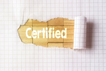 Paper tear on cube wood background with certified text