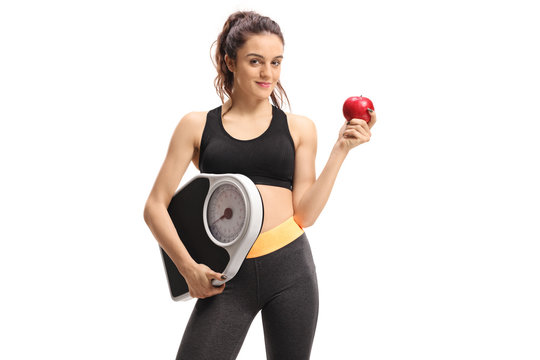 Fitness woman holding a weight scale and an apple