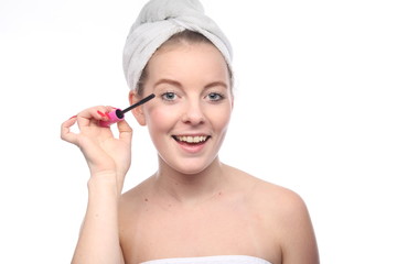 Woman applying mascara on eyelashes