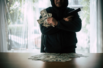 Hooded criminal gun shooting with dollar