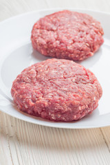 Raw hamburger patties on white plate