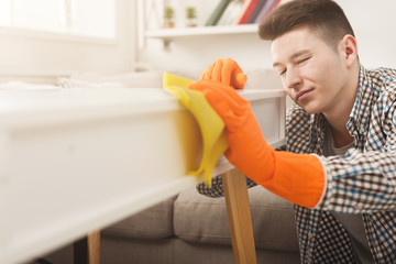 Young man cleaning home with detergents