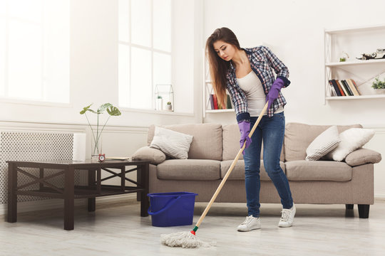 Young woman cleaning house with mop