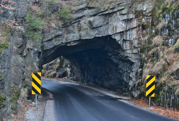 Road tunnel in rocks and warning signs