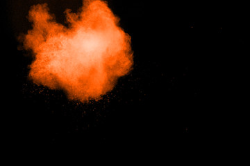 abstract orange dust explosion on  black background. abstract orange powder splattered on dark background, Freeze motion of orange powder splash. Painted Holi.
