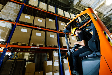 Warehouse worker doing logistics work with forklift loader